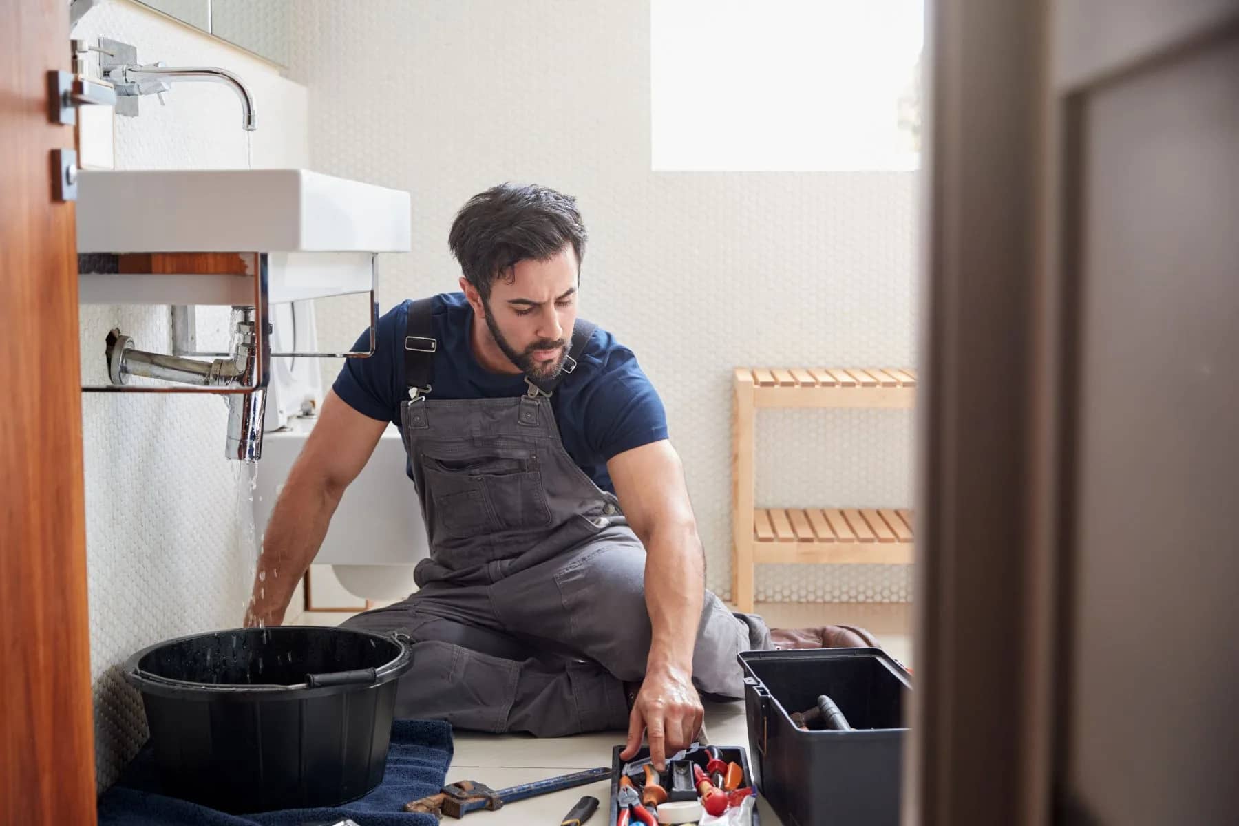 Plombier réparant la fuite d'un lavabo dans une salle de bain résidentielle