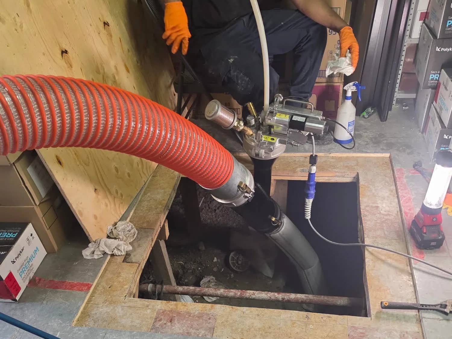 Technician installing the liner under the slab through an access opening in a warehouse floor